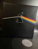 Vinyl (pleather) recreation of Pink Floyd's "Dark Side of the Moon" album cover, but with a bunny silhouette in the center, projecting out a single white line from a line of rainbow. A record made out of pleather peeps out from the album cover.