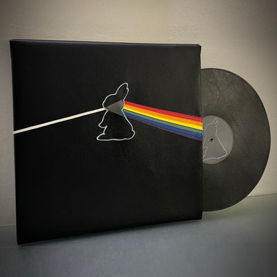 Vinyl (pleather) recreation of Pink Floyd's "Dark Side of the Moon" album cover, but with a bunny silhouette in the center, projecting out a single white line from a line of rainbow. A record made out of pleather peeps out from the album cover.