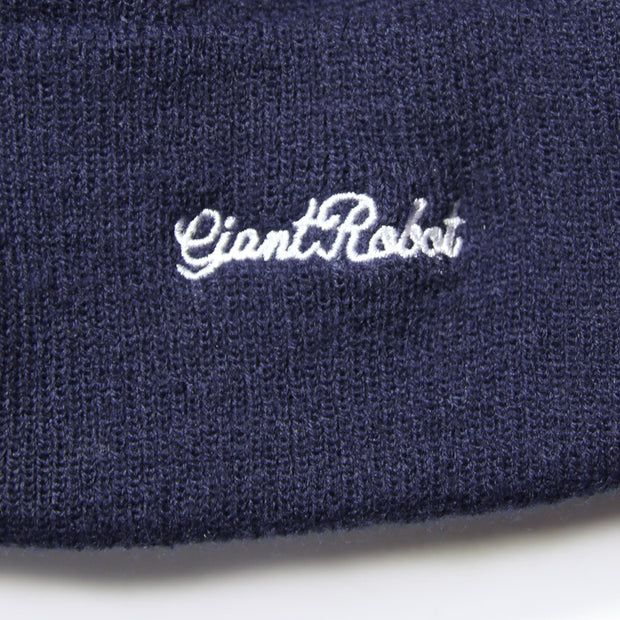 A dark navy blue knit beanie with "giant robot" stitched in cursive on the cuff in white thread