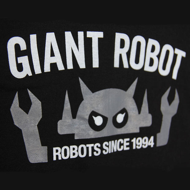 Close up of graphic on black jacket. "Giant Robot" is written in capital white font across the center, above a graphic of a gray robot head. It has 2 arms that come out of centered text that reads "robots since 1994".