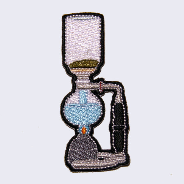 Embroidered patch of a coffee brewing device. A little flame heats up the apparatus from below. Water starts to flow up to brew the coffee.