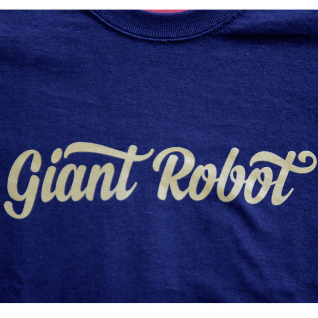 Close up of yellow cursive text that says giant robot. The "T" letters are crossed in a stylish ribbon like manner.