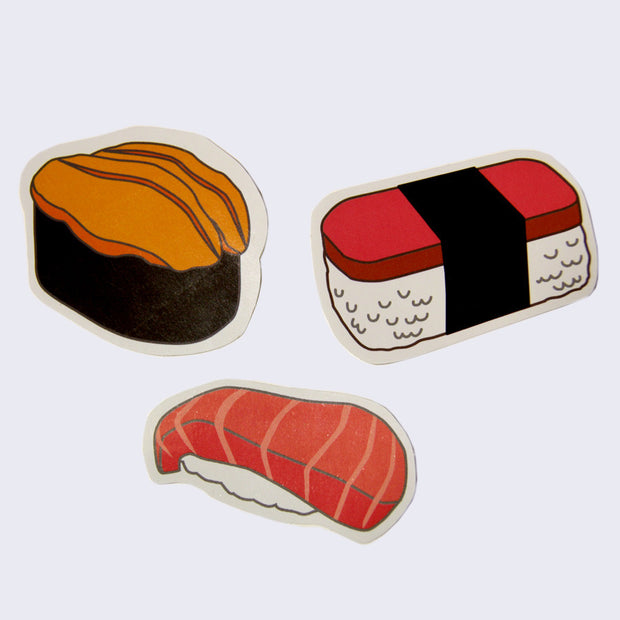3 white border die cut stickers of sushi. One is sea urchin over a seaweed wrap, one is toro salmon over rice and the last is a spam musubi.