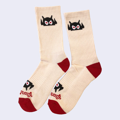 Cream colored socks with an angry cartoon robot head on cuff. The heel and toe area is red. Cursive text near toe area of sock says giant robot.