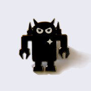 Metallic, gunmetal colored enamel pin of a robot with an angry expression and a white sparkle on its upper right chest.