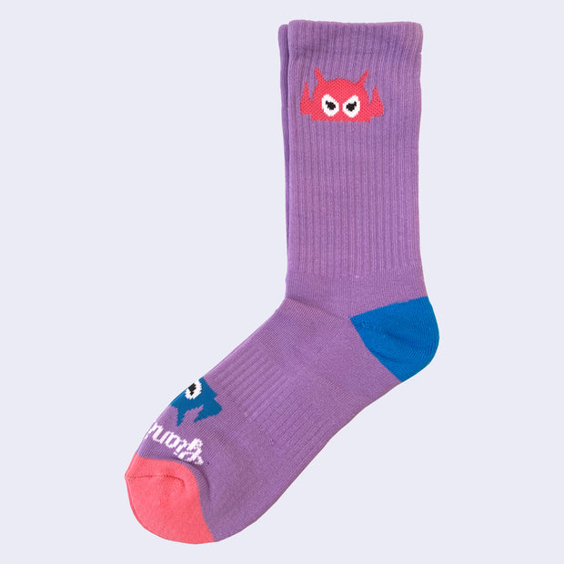 A lavender sock with angry robot head on it. The robot head on cuff is pink. The robot head near toes is blue. Text on toe area says giant robot.
