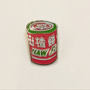 Gif of enamel pin of red, green, and white illustrated Haw Flakes wrapped candy. One image is of pin the light, the other is of pin glowing in the dark.