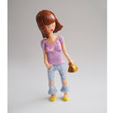 Sculpture of a woman with mid length brown hair. She wears a purple shirt that has "bitch" written on it and carries a folded paper bag.