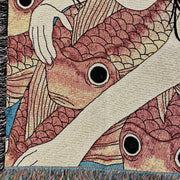 Close up detail photo of tapestry of a pink cheeked woman with long black hair, swimming amongst a densely packed group of orange koi fish.