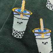 Close up of the happy boba pattern. The boba are slightly pixelated due to the knitted fabric. A sunny yellow straw pokes out of the boba's lid.