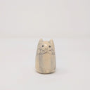 Small oval shaped cream color ceramic sculpture with little ears. It has a drawn on growling face.