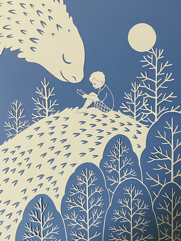 Cut paper design depicts a young child reading a book, sitting on a kind looking dragon, whose face is turned smiling to the child. A moon and trees are around the two.