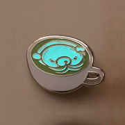 Enamel pin of a matcha latte in a shallow, white mug and a white bear design inside the cup. Pin is glowing in the dark.