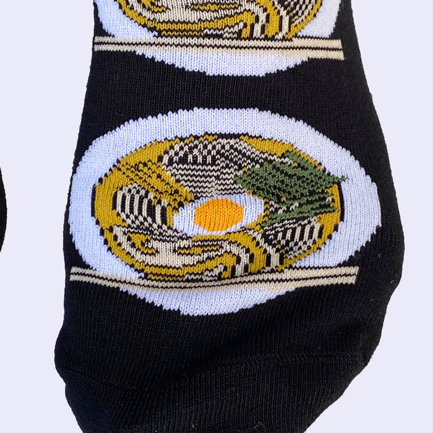 Close up of the toe area of ramen bowl socks. The ramen all have a perfectly cooked egg floating in the center.