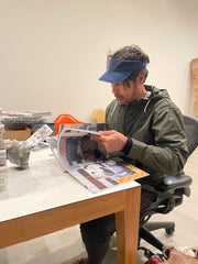 Barry McGee sits at table and is looking through his book.