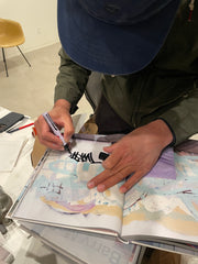 Close up of Barry McGees hands and top of head signing a book. It almost says Twist.