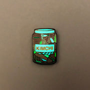 Enamel pin of glass kimchi jar glowing in the dark.