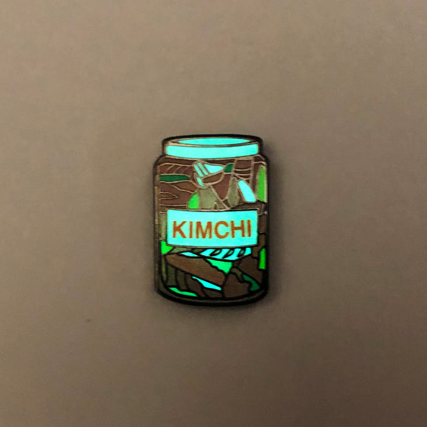 Enamel pin of glass kimchi jar glowing in the dark.