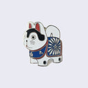 Enamel pin of a Japanese dog figure, white with black accents and wearing a blue and red flower patterned wrap.