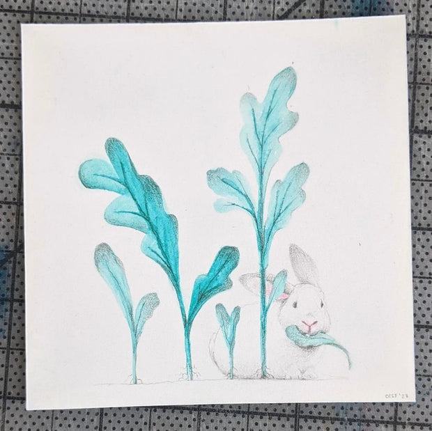 Simple drawing of a small white bunny, with a bluish green leaf in its mouth. Next to it sprout 4 large leaves out of the ground.