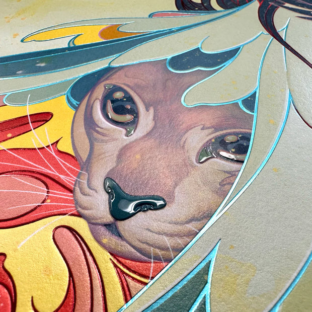 Detail of James Jean "Raven" print, a large cat, perhaps a lioness, with shiny eyes and nose looks out from under feathers. Splatters of yellow decorate the print and certain lines are metallic and raised by embossing.