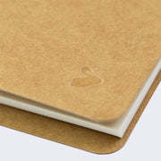 Close up of kraft colored notebook with small embossment of a swan.