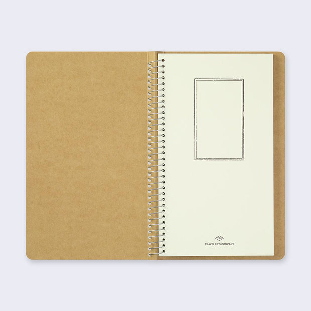 Open spread of spiral ring notebook, revealing title page. Cream colored paper with black vertical rectangle. 