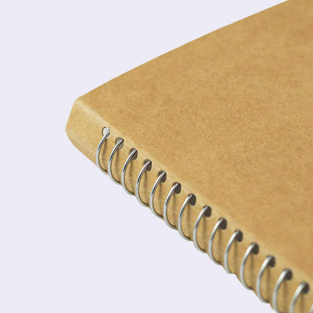 Close up of kraft colored notebook with silver metal spiral binding.