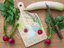 Illustration on wooden cutting board with a paddle handle of a cut up daikon radish, cut into 3 sections with small red radishes nearby. Their latin names accompany the illustrations.