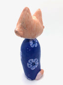 Sculpture of a large headed cartoon style orange and white cat, smiling with its eyes closed. It's wrapped in a blue floral kimono, with no limbs showing and just a tail curled around the back.