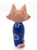 Sculpture of a large headed cartoon style orange and white cat, smiling with its eyes closed. It's wrapped in a blue floral kimono, with no limbs showing and just a tail curled around the back.