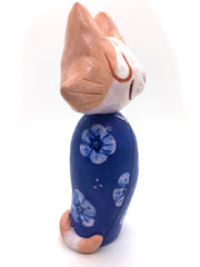 Sculpture of a large headed cartoon style orange and white cat, smiling with its eyes closed. It's wrapped in a blue floral kimono, with no limbs showing and just a tail curled around the back.