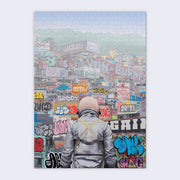 Puzzle is of an astronaut, faced away from the viewer and only visible from the waist up looking at mounts of graffiti'd containers and buildings.
