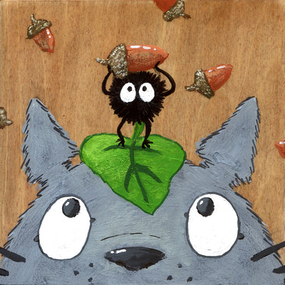 Painting of a close up Totoro face, only visible from his nose up. He looks up at a soot sprite on his head, holding up an acorn triumphantly. Background is natural wood grain with acorns as a sparse pattern.