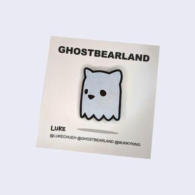 Die cut enamel pin of a ghost bear head, with minimal facial features, only eyes and a nose.