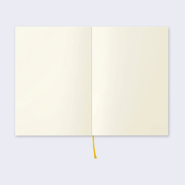 Open page spread of the notebook displaying blank cream colored paper and a red ribbon for place marking.