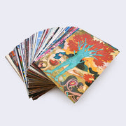 Stack of splayed out postcard with art and designs by James Jean. Top postcard displays an illustration of a tree with a human body for a trunk and bright orange leaves. 2 children stand nearby and stretch out their arms to the tree.