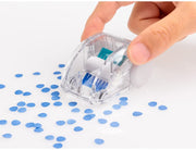 Clear plastic mini desk cleaner being moved by a hand, sweeping up small blue dots made out of paper.