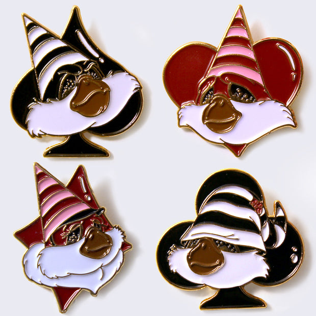 4 enamel pins, fluffy headed creatures with brown snouts and striped pointed hats. One is over a black spade, one is over a red heart, one is over a red diamond, and one is over a black club.