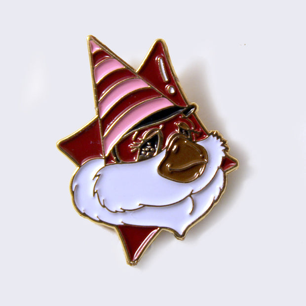 Enamel pin of a fluffy faced creature with a brown snout, and a pink and red striped triangle cap. Character is over a red diamond.