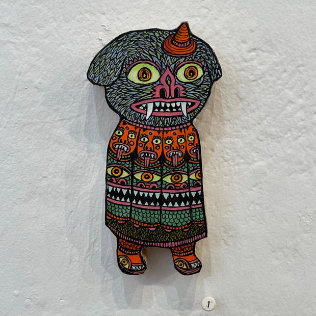 Illustrated wood cut figure of a dog faced goblin wearing a small orange wizard hat and decorated cloak, with pattern of red goblins with tongues sticking out.
