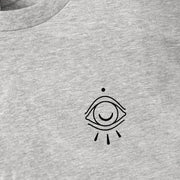 Close up of simple illustration on left chest of t-shirt. Drawing of an octopus eye.