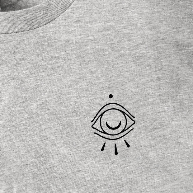 Close up of simple illustration on left chest of t-shirt. Drawing of an octopus eye.