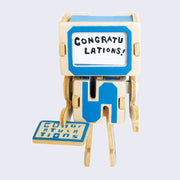 Robot face has been replaced with tiny paper card that has example text that says congratulations in blank ink.