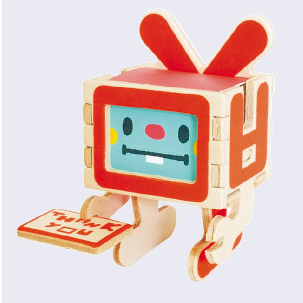 Front view of a red robot sculpture holding a thank you card made of wood. The robot has buck teeth and cute button nose.