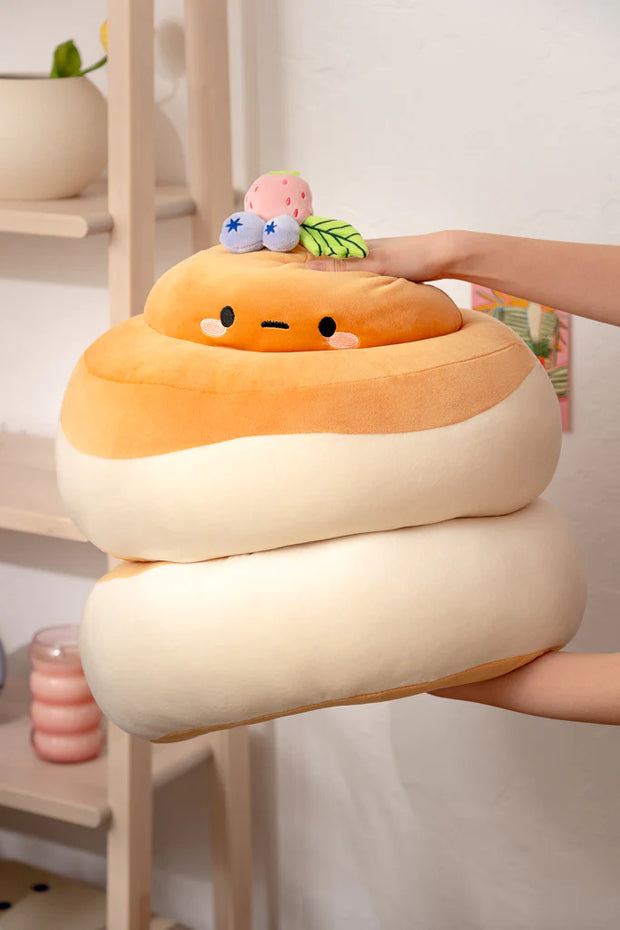  Fluffy looking stack of pancakes, in plushie form. At the top is the head of a potato character with a cute expression and berries atop its head. Plush is being squished.