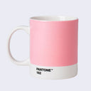 Ceramic mug, white with a white handle with a large swatch of light pink, with small black text towards the bottom of the mug that reads "Pantone 182"