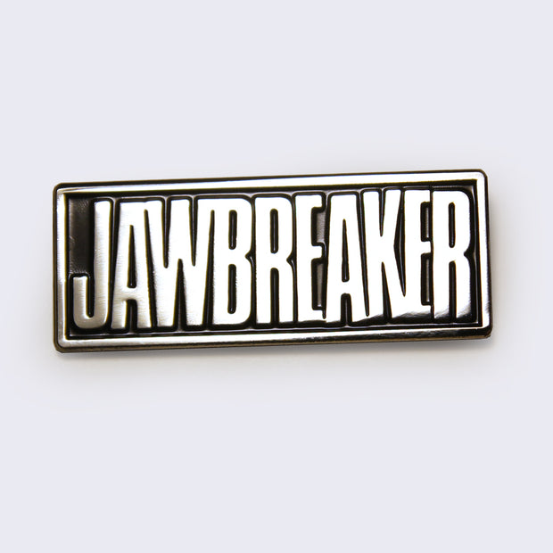 Rectangle shaped black enamel pin with silver lining and "Jawbreaker" written in silver, all caps.
