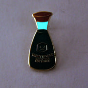 Enamel pin of a soy sauce bottle, with a red lid and small illustrated face in the middle. "Giant Robot Fresh Brewed Soy Sauce" is written along the bottle. Pin glows in the dark.