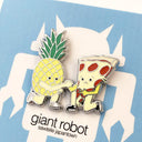 Close up of enamel pin of a pizza and a pineapple, kneeling and clasping hands.